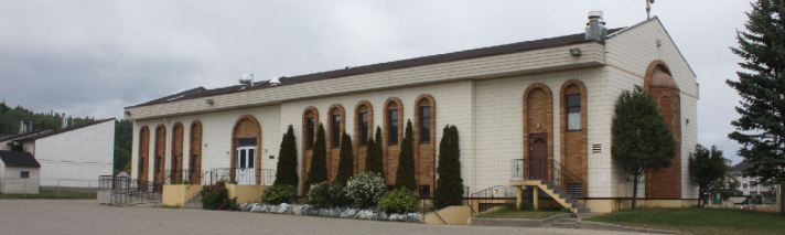 A photo of the Greek Orthodox Church in Prince George, a long cream-coloured brick building with a dark brown roof and brown brick arches over the windows and doors.